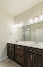 Bathroom with double vanity, hardwood / wood-style floors, and an enclosed shower