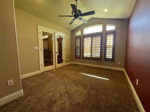 Carpeted office with ceiling fan, vaulted ceiling, and French doors