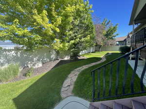 View of yard and mature landscaping with fully fenced backyard with gates on both sides