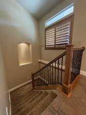 Carpeted stairway featuring wood & wrought iron railing