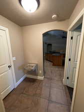 Mud room with drinking fountain, a textured ceiling, and tile floors