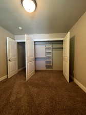 Bedroom featuring a textured ceiling, a closet, and carpet floors