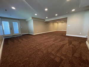 Empty room featuring dark colored carpet and basement walkout