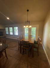 Dining space with a notable chandelier, tile flooring, and a fireplace