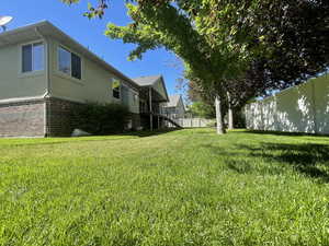 View of backyard and mature landscaping, fully fenced with gate on both sides.