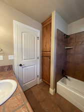 Bathroom with tile flooring, vanity, built in linen closet and tiled shower / bath combo