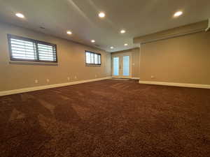 Carpeted family room with a healthy amount of sunlight and basement walkout