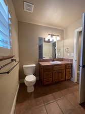 Bathroom featuring vanity with extensive cabinet space, tile flooring, and toilet