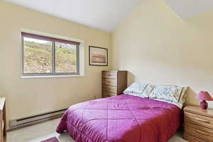 Bedroom featuring carpet flooring, baseboard heating, and lofted ceiling