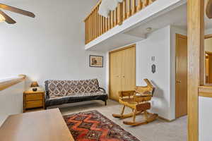 Living room featuring a towering ceiling, carpet, and ceiling fan