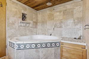 Bathroom featuring a relaxing tiled bath, wood ceiling, and tile walls