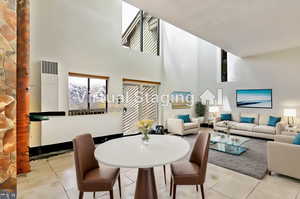 Tiled dining room with a high ceiling and a healthy amount of sunlight