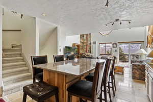 Tiled dining area featuring a textured ceiling and rail lighting