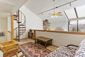 Living room with track lighting, ceiling fan, vaulted ceiling, and light colored carpet