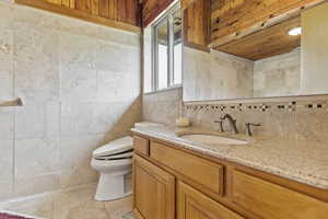 Bathroom featuring tile walls, tile flooring, toilet, and vanity with extensive cabinet space