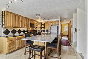 Kitchen featuring a baseboard radiator, a kitchen island, appliances with stainless steel finishes, track lighting, and tasteful backsplash