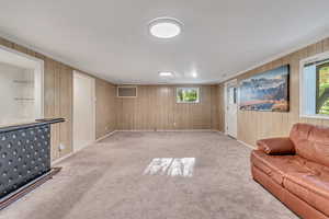 Living room with crown molding, plenty of natural light, and light colored carpet