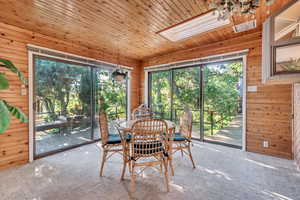 Dining area featuring a skylight, wood walls, carpet flooring, and wood ceiling