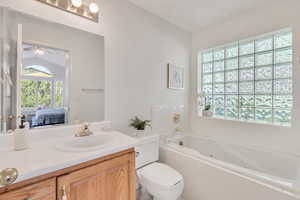 En- Suite Bathroom with a relaxing tiled bath, ceiling fan, vanity, and toilet