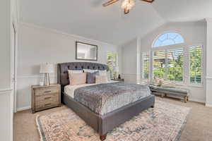 Carpeted bedroom featuring multiple windows, vaulted ceiling, and ceiling fan