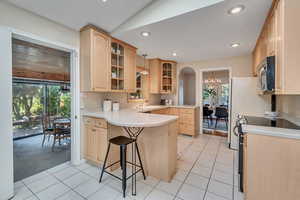 Kitchen with a wealth of natural light, electric stove, light tile floors, and kitchen peninsula