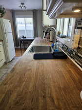 Kitchen with white refrigerator, white cabinets, sink, tasteful backsplash, and light tile flooring