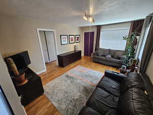 Living room with a textured ceiling and wood-type flooring