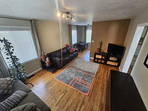 Living room with hardwood / wood-style flooring, a textured ceiling, and rail lighting