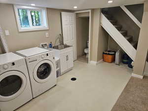 Laundry area with washer hookup, sink, washer and clothes dryer, and light carpet