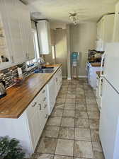 Kitchen featuring sink, white cabinets, and white appliances