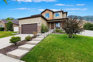 View of front of home featuring a mountain view, a porch, a garage, and a front yard