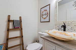 Bathroom with vanity, decorative backsplash, and toilet