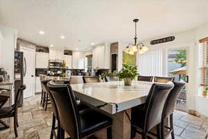 Tiled dining area with an inviting chandelier and a textured ceiling