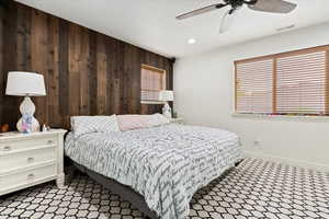 Bedroom featuring wood walls and ceiling fan