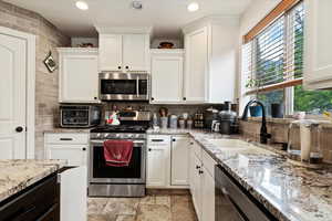 Kitchen with appliances with stainless steel finishes, light tile patterned flooring, white cabinetry, and tasteful backsplash