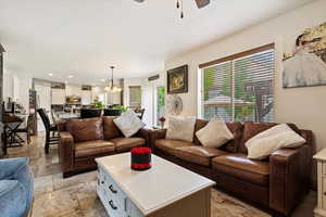 Tiled living room with ceiling fan with notable chandelier