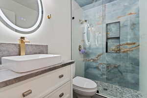 Bathroom with toilet, vanity, and an enclosed shower