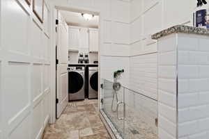 Laundry room with cabinets, washing machine and clothes dryer, and light tile patterned floors