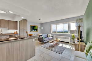 Kitchen featuring radiator heating unit, sink, pendant lighting, light tile patterned floors, and cooling unit