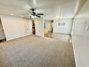 Unfurnished living room with a textured ceiling, carpet flooring, and ceiling fan