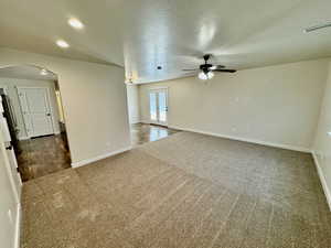 Carpeted empty room with a textured ceiling and ceiling fan