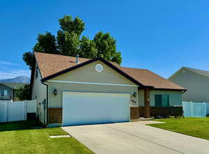 View of front of home with central AC, a garage, and a front yard