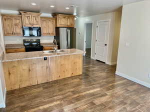 Kitchen with light stone countertops, sink, dark hardwood / wood-style flooring, and black appliances