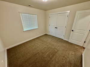 Unfurnished bedroom with a closet, carpet floors, and a textured ceiling