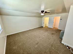 Unfurnished bedroom featuring ceiling fan, a textured ceiling, lofted ceiling, and carpet flooring