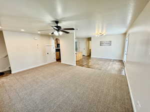 Unfurnished living room with a textured ceiling, carpet flooring, and ceiling fan