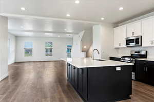 Kitchen featuring stainless steel appliances, backsplash, hardwood / wood-style flooring, an island with sink, and sink