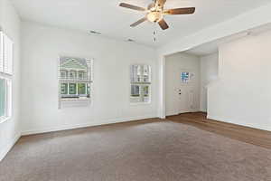 Carpeted empty room with a healthy amount of sunlight and ceiling fan