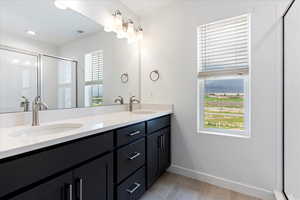 Bathroom with dual sinks, a shower with door, and large vanity