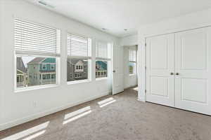 Unfurnished bedroom with light colored carpet and a closet